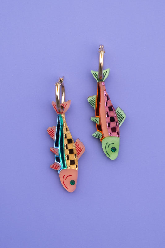 Colorful fish-shaped earrings on a purple background